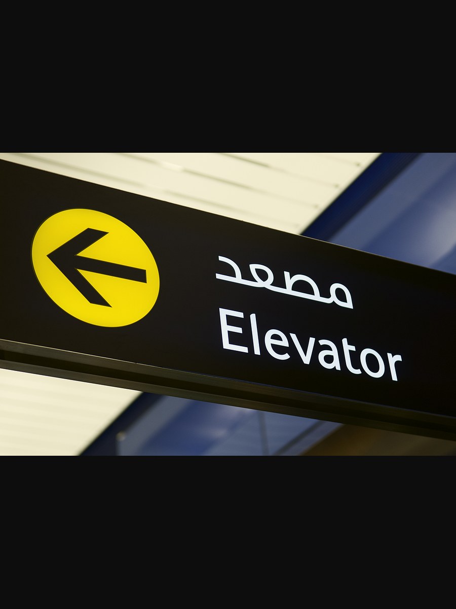 Bilingual Arabic and English elevator directional sign